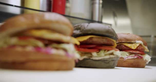肉のカットレットが付いている大きい食欲のバーガー プロのレストランキッチンで料理の料理 ハンバーガーを調理する クローズアップ おいしいバーガー 準備ができて食べる Yummyファーストフードコンセプト — ストック動画