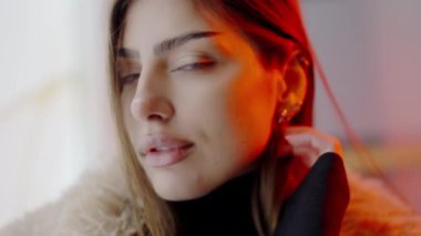 Gece şehirde neon ışıklarla yürürken genç ve çekici bir kadın kameraya bakıyor. Şehir, dışarısı, yaşam tarzı, duruş. Alacakaranlık Sokağı 'ndaki lüks kadının portresi. Şehir Bulvarı Modeli.