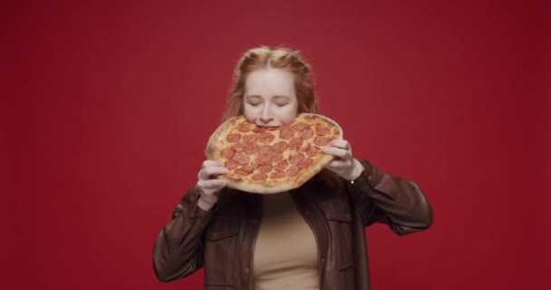 페퍼로니 피자를 아름답고 굶주린 소녀가 배경에서 즐겁게 미소짓고 있습니다 페퍼로니큰 — 비디오