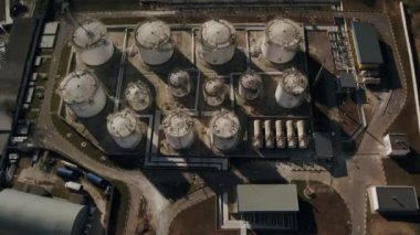 Endüstriyel bir arazide eşsiz bir heykele benzeyen çok sayıda tankın bulunduğu uçsuz bucaksız bir petrol rafinerisinin hava görüntüsü