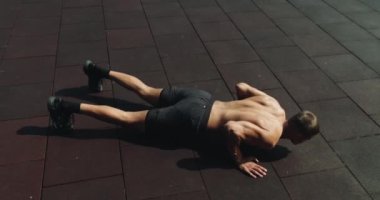 Atletik vücutlu bir adam sabah sporunu dışarıda yapar ve şınav çeker. Spor ve spor yaşam tarzı. Sporcu, kaslı, güçlü vücut geliştirici. Şınav çeker, kol pompalar.