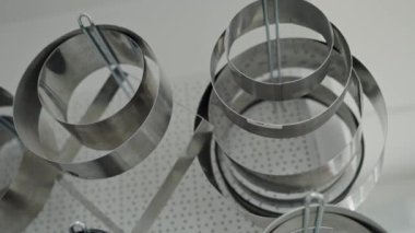 Modern bir mutfak ortamında asılı duran paslanmaz çelik halkaların zarif detaylarını gösteren yakın plan bir görüntü. Bu çekim çağdaş tasarım ve minimalizmi vurgular..