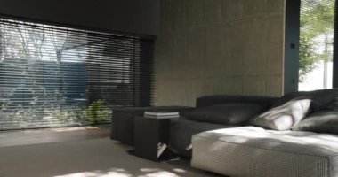 Çağdaş yatak odası, pencere perdelerinden süzülen büyük bir yatak odası, beton duvarlar ve çevre güneş ışığı sergiliyor. Beton Duvarları ve Şık Perdeleri olan Modern Oturma Odası