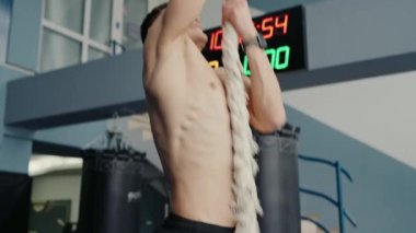 Spor salonunda tırmanma ipini tutan bir insanın yakın çekim görüntüsü, güç ve kararlılığı vurguluyor. Spor salonundaki tırmanma halatı, Eller ve Halata Odaklanma