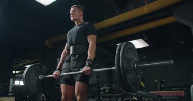 Endüstriyel tarzda bir spor salonunda ağırlık kaldıran erkek sporcu formda ve kararlı görünüyor. Modern Spor Salonunda Deadlift Yapan Genç Adam