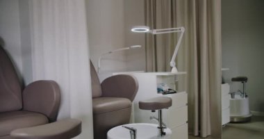 Rahat bir sandalyenin, şık beyaz çalışma yerlerinin ve profesyonel bir manikür lambasının olduğu temiz ve iyi organize edilmiş bir manikür salonu. Çağdaş güzellik tedavileri tasvir etmek için ideal