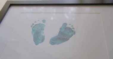 Beyaz arka plan kağıdındaki bebek ayaklarının yeşil izleri. Renkli akrilik boya ve tuval üzerindeki ayak izlerinin büyüleyici bileşimi. Sanatsal yaratıcı ifade. Bebek ayağı..