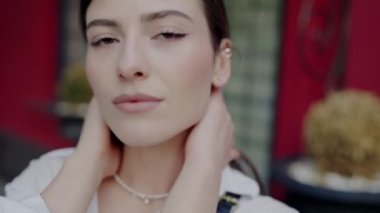 Yüksek çözünürlüklü bir yakın plan genç bir kadının sakin yüzünü tasvir ediyor. İnce gülüşüne ve detaylı yüz hatlarına odaklanıyor. Tarafsız İfadeli Genç Bir Kadının Yakın Çekim Portresi