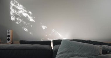Rahat koltuklar ve minimalist bir dizaynla pencereye gölge düşüren dokulu güneş ışığıyla çağdaş bir oturma odası. Modern Oturma odası