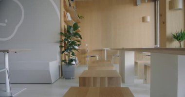 Ahşap masa ve sandalyelerin, beyaz minimalist tasarımın ve yemyeşil bitkilerin yer aldığı parlak ve modern bir ofis kafeteryası. konfor ve işlevsellik için tasarlanmış modern çalışma alanı.