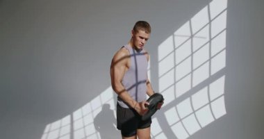 23 yaşında atletik yapılı bir erkek stüdyo ortamında ağırlık çalışması yapıyor. Gölge oyunu dramatik bir etki yaratıyor. Stüdyoda Güçlendirme Eğitimi Yapan Atletik Genç Adam