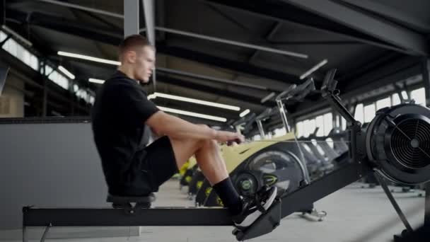 Jovem Focado Exercitando Uma Máquina Remo Ginásio Moderno Demonstrando Aptidão — Vídeo de Stock