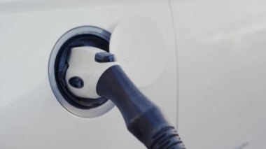 EV şarj istasyonu, temiz enerji dolum teknolojisi, elektrikli araba şarjı. Şarj istasyonunda bir arabaya şarj oluyor. Elektrikli aracın kavramsal görüntüsü. Sürdürülebilir güç için yenilenebilir enerji altyapısı