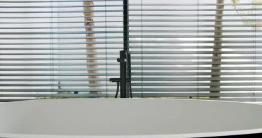 Modern ofis ortamında temiz, boş bir masa, arka planda doğal bir manzaraya bakan odaklanmış pencere perdeleri. Perdeler Arasında Görünümü Olan Modern Banyo İçi