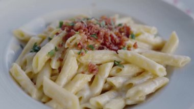 Kıtır Pastırmalı Kremalı Makarna ve Taze Maydanoz. Kıtır kıtır pastırmalı ve üzerine taze maydanoz serpiştirilmiş, beyaz bir tabakta servis edilen kremalı makarna..