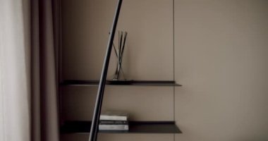 Minimalist bir iç mekan, zarif raf düzenini vurgulamak, yumuşak ortam aydınlatması ve rahatlatıcı bir renk paleti. Karanlık Dekor ve Yumuşak Işıklı Minimalist İç Tasarım