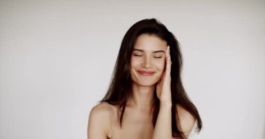 Yüzü sağlıklı, temiz, yeni ciltli beyaz duvarda güzel bir bayan model. Mükemmel genç ten ve güzellik kavramı. Güzellik videosu konsepti, yakın plan portre. Şirin Moda Modeli.