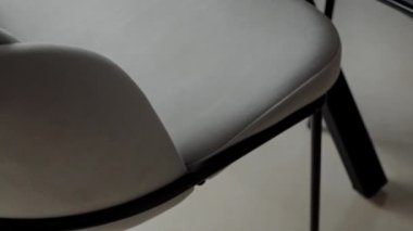 Pürüzsüz, gri bir ofis sandalyesinin, sadeliği ve modern tasarımı vurgulayan, minimalist siyah metal çerçevesiyle tamamlanmış yakın çekimi. Minimalist Siyah Çerçeve Ayarında Modern Gri Sandalye