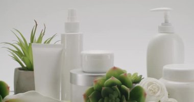 Beyaz şişe ve kozmetik çiçekli tüpler stüdyoda beyaz bir arka planda, zum yap. Doğal malzemelere dayalı kozmetik yağları, fırça, tonik, vücut bakımı. Kremalı parlak kozmetik kavanozu