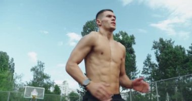 Atletik vücutlu genç bir adam koşuyor ve dışarıda yoğun bir idmandan önce ısınıyor. Yalnız başına antrenman yapan güçlü bir sporcu. Dışarıda spor yapan adam dışarıda antreman yapıyor..