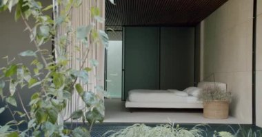 Zarif bir minimalist yatak odası, gür iç mekan bitkileriyle, sakin, yeşil ve bej renkli, modern ev dekorasyonu için mükemmel. Kapalı Çiçekli Modern Yatak Odası