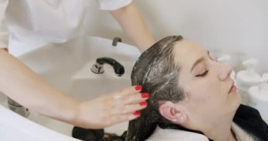 Kuaförde saç yıkayacağım. Bir kadın saçını yıkar ve boyama işleminden sonra saçındaki kahverengi boyayı yıkar. Saç bakımı. Güzellik stüdyosunda genç bir kadın..