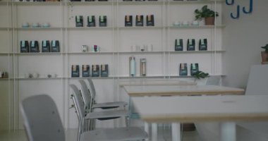 Bu resim, minimalist tarzda ve organize raflarla modern bir kafenin içini gösteriyor. Düzgün düzenlenmiş kahve ürünleri ve zarif mobilyalarla sakin ve şık bir atmosferi ön plana çıkarıyor.