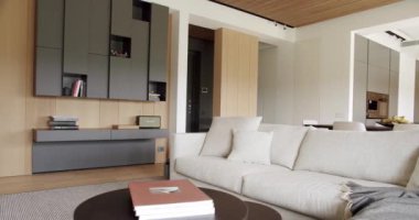 Ahşap duvarlı ve gri mobilyalı modern oturma odası. Köşedeki kanepe ve kitaplığı olan modern bir ev. Minimalist İç İşleri. Samimi Modern Mobilya Tasarımı. Lüks Zarif Oda