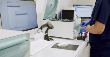Male doctor places the blood tests in the centrifuge. From above centrifuge machine with test tubes spinning then stopping during workday in modern lab. Centrifuge machine with vials in laboratory.