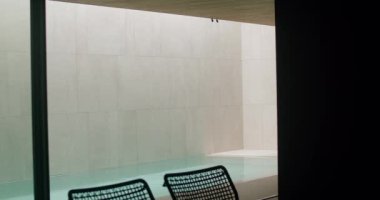 Sakin bir havuzu ve şık siyah sandalyeleri olan, sakin ve sakin bir atmosferi somutlaştıran minimalist bir tasarıma sahip şık ve sakin bir iç mekan. Zarif Havuz ve Oturma Alanı ile Modern İç Kesim