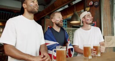 Mutlu karışık ırk destekçileri kazandıktan sonra seviniyor ve tezahürat yapıyorlar. Bardaki arkadaşlar eğleniyorlar. Büyük Britanya 'nın bayrağıyla bira içip maç izleyen adamlar.