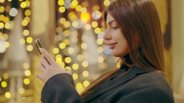 İş kadını, ortaklarıyla önemli e-postalar atarak akşam çalışmaya devam ediyor. Modern teknolojiler kullanır. İnternetten alışveriş ve restoranda mesajlaşan kadın. Çevrimiçi iletişim.