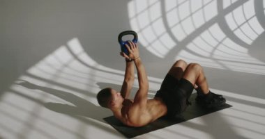 Stüdyoda kettlebell ile antrenman yapan 23 yaşında fit bir adam. Atletik erkek egzersiz yapıyor, güce odaklanıyor. Stüdyoda Kettlebell ile Spor Yapan Adam
