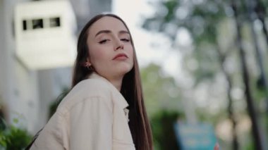 Dışarıda poz verirken kendine güvenen genç bir kadın. Yumuşak doğal ışık, bulanık bir arkaplan ile yüz hatlarını ön plana çıkarıyor. Güven, güzellik ve yaşam tarzı gibi konular için ideal.