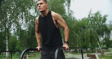 Young Athlete in Sportswear Doing Pull-Ups Exercise on Horizontal Bars at Outdoor Fitness Park. Sports, health care, fitness routine, workout. Strength, motivation. Outdoors gym.