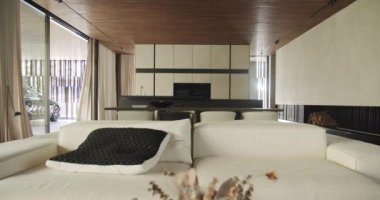 Stylish modern living room seamlessly blends with a sophisticated kitchen area, featuring a minimalist decor and large windows. Elegant Modern Living Room with Integrated Kitchen Design