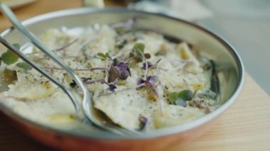 Taze otlarla süslenmiş, metal bir tabakta servis edilen nefis kremalı ravioli tabağının yakın çekimi. İtalyan yemeği için mükemmel. Lezzetli Kremalı Ravioli Tabağı ile Taze Herb Garnitür Metal Tabakta