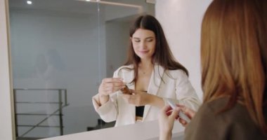 Kadın müşteri güzellik salonunda yüz bakımı için kremi seçiyor. Kadın danışman cilt bakımı için profesyonel kozmetik ürünler öneriyor. Cilt bakımı ürünü seçen kadın.