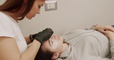 Woman Eye with Long Eyelashes. Eyelashes extensions. Fake eyelashes. Eyelash extension procedure. Professional stylist lengthening female lashes. Master and client in beauty salon