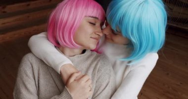 Couple, lgbt and lesbian women at home. Embrace and holding each other. Love and kiss, Pride Event, friendship concept. Romance and portrait of lesbian couple with blue and pink hair enjoying.