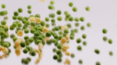 Many ripe green peas and corn grains rolling on a reflective surface on an isolated white background. Close up Fresh green peas and corn grains. Fresh green pea and maize on white background.