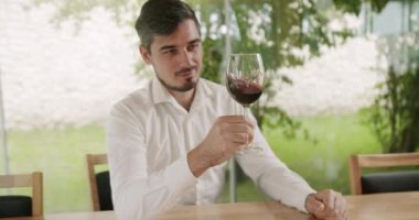 Camların dönüşü şarabın yüzeyini dalgalandırıyor ve uzun cam duvarlar boyunca uzanıyor. Sommelier şarap kadehini sallıyor ve tadına bakıyor. Şarap yapımı konsepti.