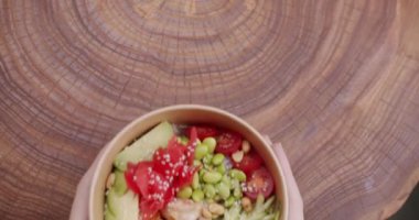 Diyet öğle yemeğinde taze balık ve sebze. Japon yemeği, karides, pirinç, avokado, mango, edamame fasulyesi, ahşap zemin üzerinde salatalık. Poke kasesi, geleneksel Hawaii çiğ balık salatası..