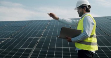 Technician inspect Solar cell Farm through field of solar panels. checking the panels at solar energy installation. Solar cells will be an important renewable energy of the future.