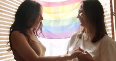 Kız sevgilisinin eline nişan yüzüğünü takıyordu, Lgbt bayrağında romantik bir kutlamanın tadını çıkarıyordu. Mutlu lezbiyen çift. Sevgiler ve öpücükler, lezbiyen aile. LGBT ilişkiler kavramı