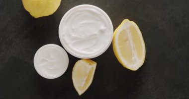 Üst Manzara Beyaz Şişe ve kozmetik için limonlu tüpler stüdyoda siyah bir arka planda dönüyor. Saç ve cilt bakımı için doğal kozmetik ürünleri. Farklı kozmetik şişelerden oluşan bir grup. Üst görünüm.