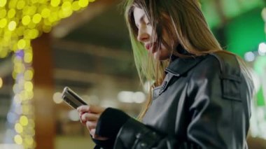 Modern teknolojiler kullanır. Çevrimiçi alışveriş ve şehir merkezinde telefonla mesajlaşan bir kadın. Çevrimiçi iletişim. Sevimli modern kadın düzenleme buluşması.