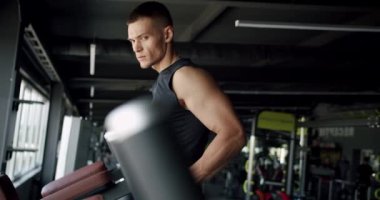 Genç ve kararlı bir erkek olarak yoğun bir egzersiz, spor aletleri kullanarak gücünü arttırır. Sağlık ve zindelik temalarını iletir. Odaklanmış Genç Adam Spor Salonu Ekipmanını Spor Salonu Eğitimi İçin Kullanıyor