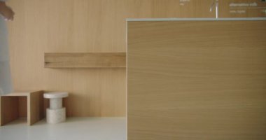 Bir kadın olarak yakalanan modern bir yaşam tarzı bir kafede tezgahın yanında duruyor ve alternatif süt seçeneklerini düşünüyor. Dekor minimalist, ahşap elementlerle huzurlu ve temiz bir ortam sergiliyor..