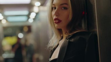 Renkli ışıklarla aydınlatılmış modern bir şehir ortamında tek başına duran düşünceli bir kadının profili. Düşüncelere dalmış, yalnızlık ve içgözlem duyguları uyandırıyor..